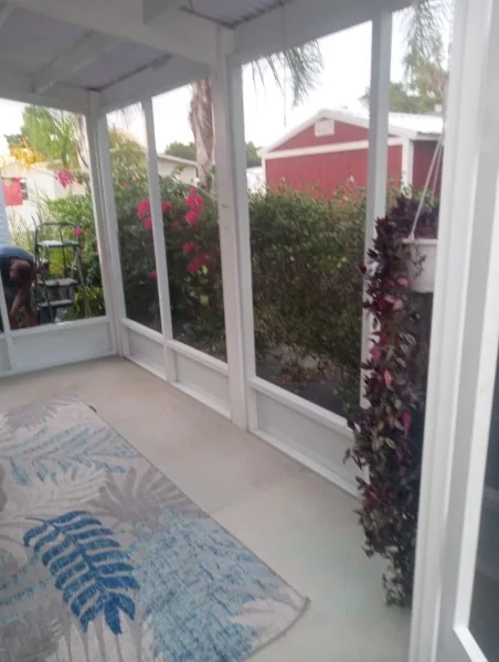 Screened room framing and garden view during work, with a worker at the left