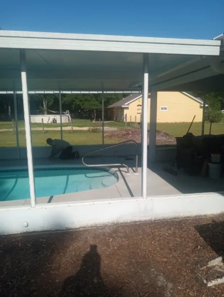 White pool screen enclosure and entry railing with a person working nearby